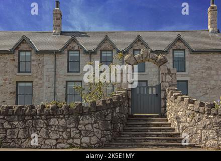 Scalini che conducono verso l'alto ad una porta ad arco di fronte ad una casa entrambi realizzati in pietra di colore pallido nero Foto Stock