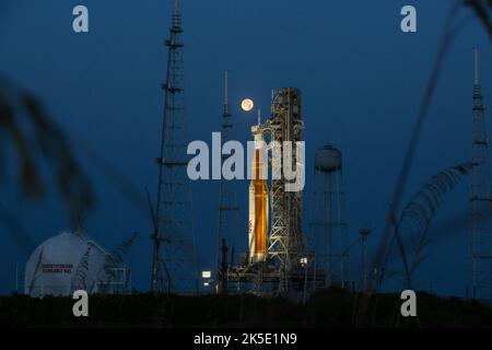 Una Luna piena è in vista dal Launch Complex 39B al Kennedy Space Center della NASA in Florida il 14 giugno 2022. Il sistema spaziale Artemis i Space Launch System (SLS) e la navicella spaziale Orion, in cima al lanciatore mobile, sono in preparazione per una prova di vestito bagnato per praticare le tempistiche e le procedure per il lancio. La prima di una serie sempre più complessa di missioni, Artemis i testerà SLS e Orion come sistema integrato prima dei voli con equipaggio per la Luna. Attraverso Artemis, la NASA atterrà la prima donna e la prima persona di colore sulla superficie lunare, spianando la strada ad una presenza lunare a lungo termine e utilizzando il Moo Foto Stock