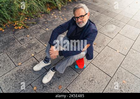 Uomo anziano barbuto in occhiali da sole rave al neon incandescente  guardando lontano su sfondo rosa Foto stock - Alamy