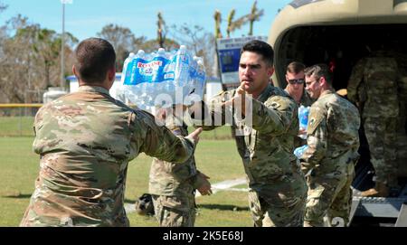 Guardia nazionale dell'esercito della Florida SPC. Carlos Pera e SPC. Diego Garcia assegnato a Bravo Company, 753rd Brigade Engineer Battalion scaricare casi di acqua da un Boeing US Army Boeing CH-47 elicottero Chinook durante gli sforzi di risposta di emergenza da parte dell'uragano Ian a Pine Island Florida 3 ottobre 2022. L'elicottero forniva cibo e acqua per coloro che erano in missione a Pine Island e per distribuire ai residenti effettuati dalla distruzione dell'uragano Ian. (Foto di credito della Guardia Nazionale dell'Esercito della Florida da parte di staff Sgt. Cassandra Vieira) Foto Stock