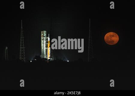 Una Luna piena è in vista dal Launch Complex 39B al Kennedy Space Center della NASA in Florida il 14 giugno 2022. Il sistema spaziale Artemis i Space Launch System (SLS) e la navicella spaziale Orion, in cima al lanciatore mobile, sono in preparazione per una prova di vestito bagnato per praticare le tempistiche e le procedure per il lancio. La prima di una serie sempre più complessa di missioni, Artemis i testerà SLS e Orion come sistema integrato prima dei voli con equipaggio per la Luna. Attraverso Artemis, la NASA atterrà la prima donna e la prima persona di colore sulla superficie lunare, spianando la strada ad una presenza lunare a lungo termine e utilizzando il Moo Foto Stock
