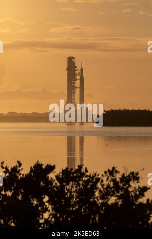 Un’alba al Kennedy Space Center della NASA in Florida proietta un bagliore arancione attorno al razzo Artemis i Moon dell’agenzia mentre si reca al Launch Complex 39B il 6 giugno 2022. Il razzo è uscito dal Vehicle Assembly Building nelle prime ore del mattino per percorrere le 4,2 miglia fino al piazzale di lancio per il prossimo tentativo di prova di abbigliamento bagnato della NASA prima del lancio di Artemis I. La prima di una serie di missioni sempre più complesse, Artemis i testerà il razzo Space Launch System e la navicella spaziale Orion come sistema integrato prima dei voli con equipaggio verso la Luna. Attraverso Artemis, la NASA sbarcherà la prima w Foto Stock