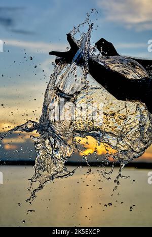 Un pallone d'acqua che scoppierà contro un cielo al tramonto. Foto Stock