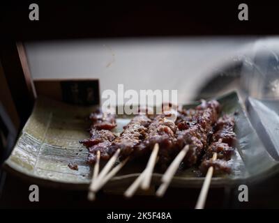 Stecche di maiale alla griglia sul fuoco fiammeggiante in acciaio stufa stile vintage, delizioso cibo di strada tailandese e concetto popolare. Foto Stock