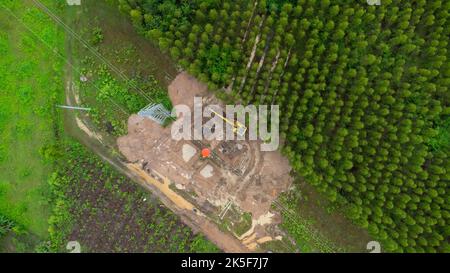 La vista aerea degli escavatori sta lavorando sulle fondamenta dei tralicci ad alta tensione e sulle gambe dei poli ad alta tensione. Vista dall'alto della costruzione della potenza Foto Stock