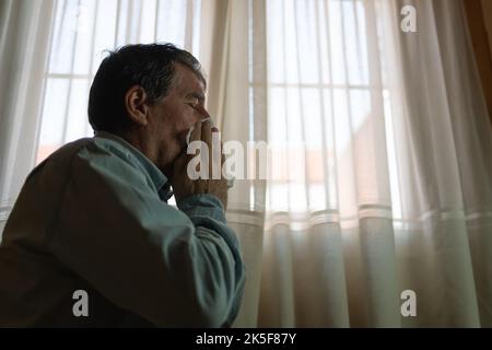 Malato di influenza e starnuti in un tessuto, seduto a casa. Foto Stock