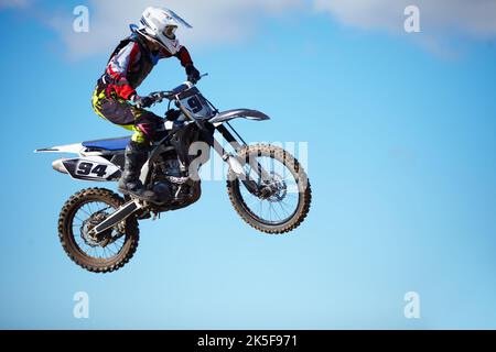 Impostazione dei suoi punti di vista in alto. Un motociclista a mezz'aria contro un cielo blu. Foto Stock