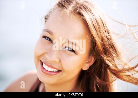 Il suo sorriso illuminerà la vostra giornata. Una giovane donna stupefacente sorridente alla macchina fotografica. Foto Stock