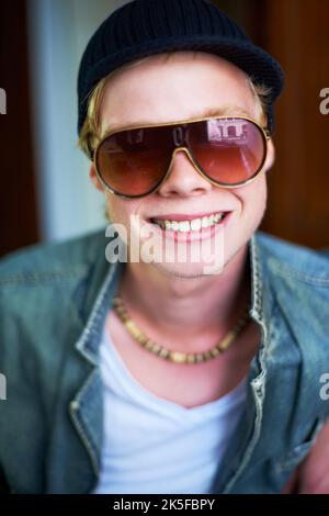 HES non ha paura di darti un sorriso. Giovane ragazzo in abbigliamento urbano che ti dà un grin cheesy. Foto Stock