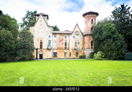 ITALIA, MIRADOLO - CIRCA AGOSTO 2020: Castello di design gotico situato in un giardino all'italiana, pieno di mistero, con luce del tramonto. Foto Stock