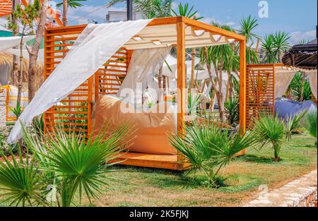 Bellissimo paesaggio - spiaggia lounge area - lettini in legno con sedie a sdraio, prati verdi e palme Foto Stock