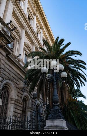 Lampada da strada ornata con palme e facciata dall'architettura romana classica Foto Stock