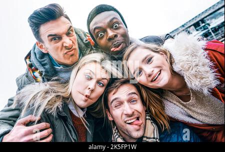 I migliori amici multirazziali prendono selfie all'aperto sui vestiti di inverno di autunno - concetto felice di gioventù con la gente millennial che si diverte insieme - Multicultur Foto Stock