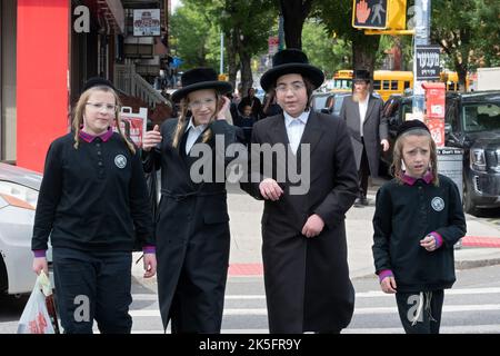 4 ragazzi ebrei ortodossi con lunghe passeggiate a piedi lungo Lee Avenue a Williamsburg, Brooklyn, New York. I 2 alle estremità sono fratelli. Foto Stock