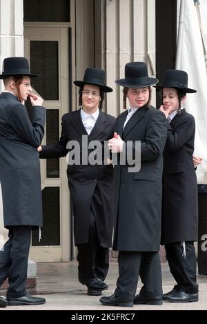 4 ragazzi hassidici vestiti di nero davanti a una sinagoga a Williamsburg, Brooklyn, New York City. Foto Stock
