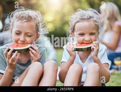 Felice, pic-nic e anguria con bambini in parco con la famiglia per l'estate, benessere e relax. Salute, natura e primavera con i bambini che mangiano frutta Foto Stock