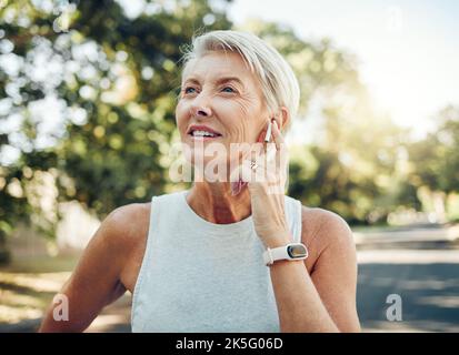 Cuffie per donna anziana, fitness e musica per allenarsi, allenarsi o fare esercizio nel parco naturale o nel giardino svedese. Pensare persona matura ascoltare Foto Stock