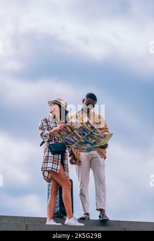 Due persone bellissime sono alla ricerca di mezzi di trasporto sulla mappa. Vogliono tornare a casa prima che piovano Foto Stock