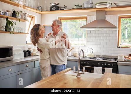 Danza, coppia e cucina con un uomo anziano e una donna che ballano insieme in una casa di riposo. Amore, libertà e romanticismo con un anziano maschio e femmina Foto Stock