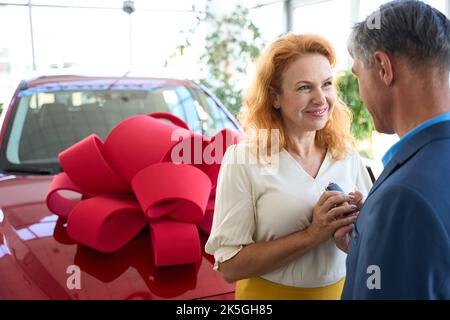 La donna prende le chiavi da un'auto donata dall'uomo Foto Stock