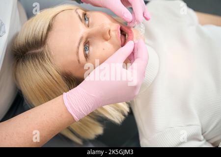 Il dottore in guanti rosa mette gli allineatori su un paziente Foto Stock