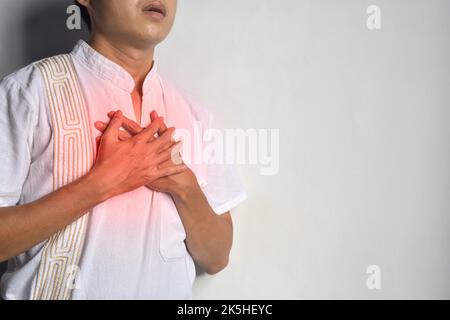 Giovane asiatico che soffre di costrizione toracica. Può essere causato da asma, bronchite, bronchiolite, polmonite, infarto miocardico, ischemica h Foto Stock