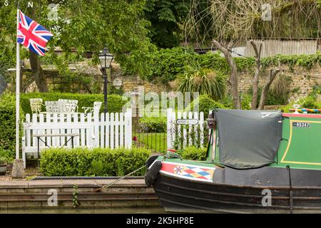 NORTHAMPTONSHIRE, Regno Unito - 25 maggio 2022. Waterside giardino vicino al canale nel villaggio di Stoke Bruerne, con narrowboat e Union Jack Foto Stock