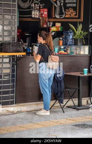 giovane donna che ordina un caffè in una caffetteria da asporto o vendoe di bevande di strada sull'isola greca di zante in grecia. signora che ordina un drink al bar Foto Stock