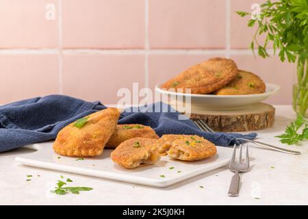 Polpettine di carne e foglie di prezzemolo su piatti di ceramica bianca in una cucina da banco. Foto Stock