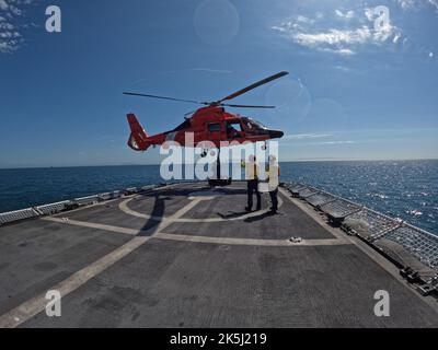 Un equipaggio di elicotteri a bordo di un elicottero MH-65 Dolphin dalla Stazione aerea Humboldt Bay conduce un rifornimento verticale con la Cutter Cutter Constalfast della Guardia Costiera (WMEC 623) mentre Constalfast pattugliava l'Oceano Pacifico, 16 agosto 2022. Il 3 ottobre 2022, dopo una pattuglia contro la narcotica di 55 giorni, Stafast tornò al loro Astoria homeport. Foto della Guardia Costiera degli Stati Uniti. Foto Stock