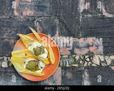 Due tamales di Oaxacan su un piatto di argilla fatto con hoja babbo natale e riempito di fagioli Foto Stock