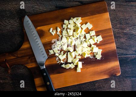 Cioccolato bianco tagliato su un tagliere di legno: Pezzi di cioccolato bianco con un coltello da cucina su un tagliere di legno Foto Stock