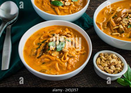 Zuppa di noodle piccante di zucca al curry tailandese guarnita con arachidi e basilico tailandese: Zuppa spessa o stufato a base di zucca, tagliatelle di riso e funghi shiitake Foto Stock