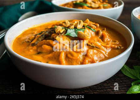 Zuppa di noodle piccante di zucca al curry tailandese guarnita con arachidi e basilico tailandese: Zuppa spessa o stufato a base di zucca, tagliatelle di riso e funghi shiitake Foto Stock