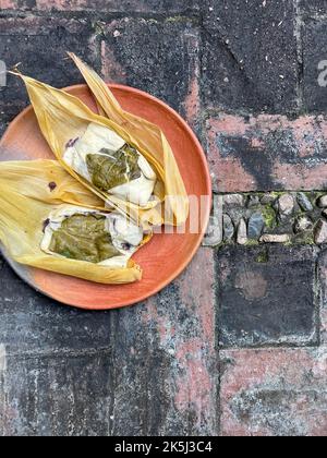 Due tamales di Oaxacan su un piatto di argilla fatto con hoja babbo natale e riempito di fagioli Foto Stock