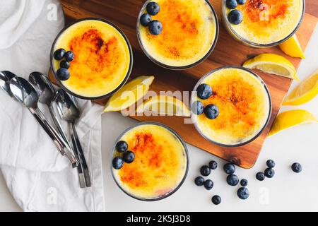 Mirtillo-arancia Creme Brulee Dessert guarniti con freschi Blueberries: Vista dall'alto della crema sulla confettura di mirtilli ricoperti di zucchero caramellato Foto Stock