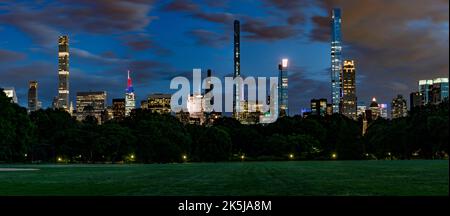 Skyline di Midtown Manhattan di notte da Central Park panorama con prato erboso in primo piano. Foto Stock