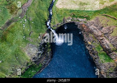 Una vista aerea della cascata di Mulafossur nel villaggio di Gasaladur sull'isola di Vaga, Isole Faroe Foto Stock