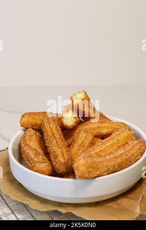 primo piano dei churros con lo zucchero nel recipiente bianco, vista dall'alto Foto Stock