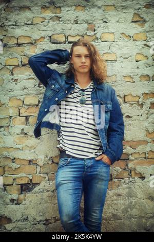Appena appeso intorno. Ritratto di un bel giovane appoggiato su un muro di mattoni. Foto Stock