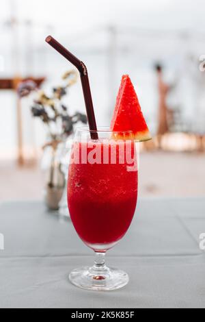 Frullato di cocomero fresco e rosso brillante in un bicchiere di vetro in piedi sul tavolo Foto Stock