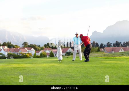 L'uno corrispondente all'altro scatto per scatto. Due amici maschi che si godono una giornata sul campo da golf. Foto Stock
