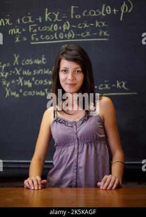 Fisico futuro. Ritratto di un giovane studente in piedi di fronte a un'equazione matematica su una lavagna a gesso. Foto Stock