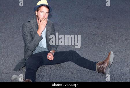 HES hip e bello. Un bel hipster seduto fuori sulla strada. Foto Stock