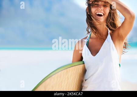 Posso vedere il vostro messaggio che fa le onde in questo copyspace. Bella ragazza spazzando i capelli fuori del suo viso tenendo la tavola da surf prima di colpire le onde - Foto Stock