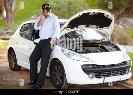 La mia auto si è rotta... Un uomo che chiama l'assistenza stradale sul suo cellulare perché la sua auto si è rotta. Foto Stock