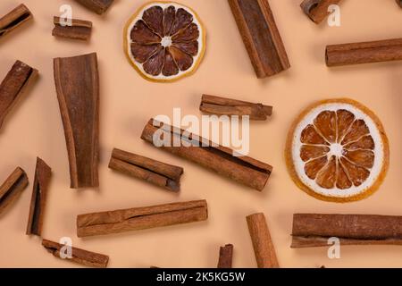 sfondo con bastoncini di cannella e fettine essiccate di limone o arancia su sfondo beige, cibo accogliente, sfondo speziato alla moda. Foto Stock