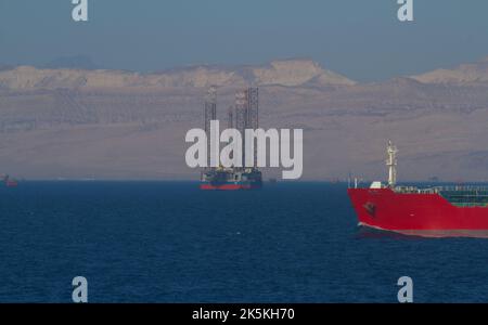 Piattaforma di perforazione petrolifera in mare rosso con le montagne del Sinai sullo sfondo e una nave che si inchina in primo piano Foto Stock