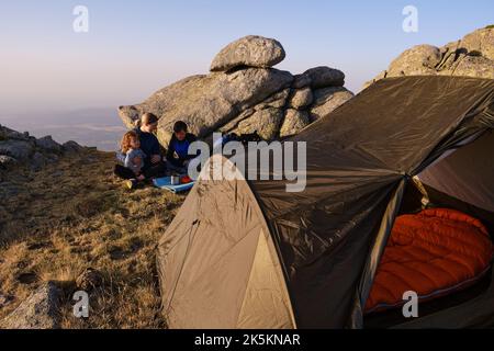 Famiglia di viaggiatori che consumata la colazione fuori dalla tenda Foto Stock