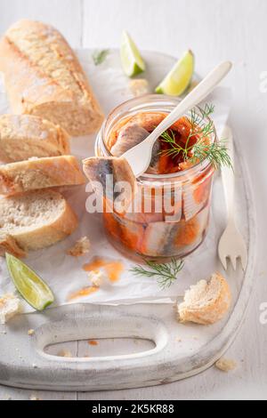 Pesce marinato fresco e delizioso come fonte di grassi sani. Aringa in vaso servita con pane. Foto Stock